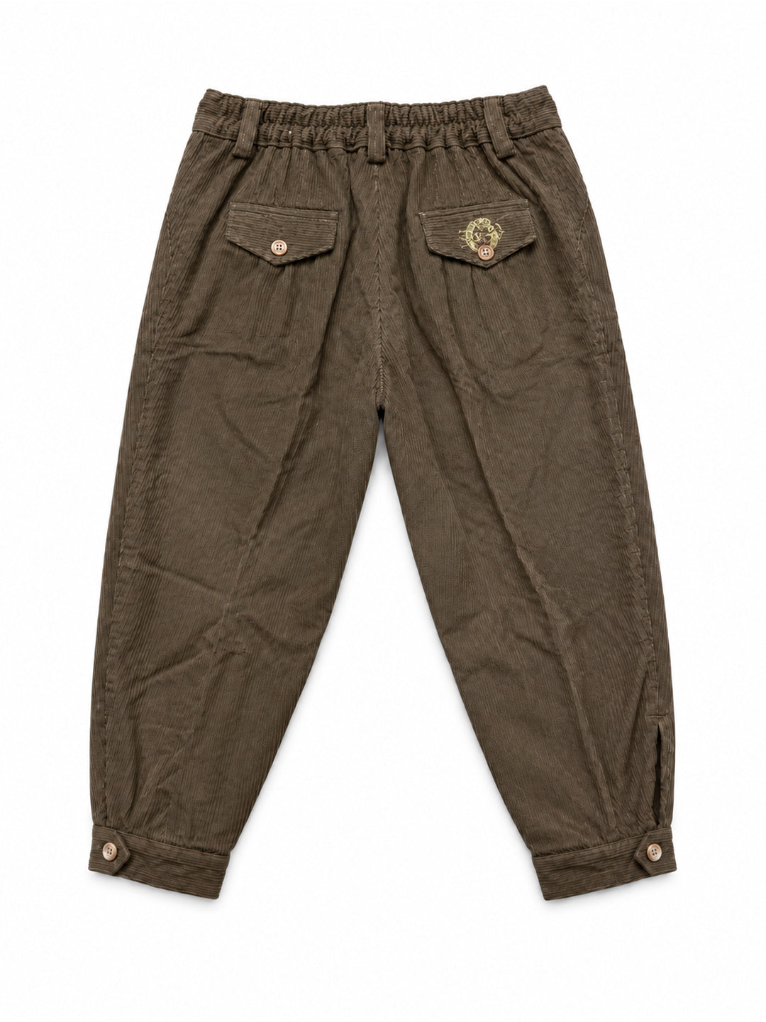 A pair of dark brown corduroy pants with an elastic waistband, featuring flap pockets on the back with snap buttons and a circular embroidered patch on the right pocket, shown against a plain white background. Argentine Bombacha Pants, horseback riding, traditional gaucho, Argentine cowboy attire. Soft and breathable fabrics, perfect pants for all-day wear. With a loose fit and elasticated waistband, they allow for plenty of movement, while the high waist provides extra coverage. Everyday look, perfect for 